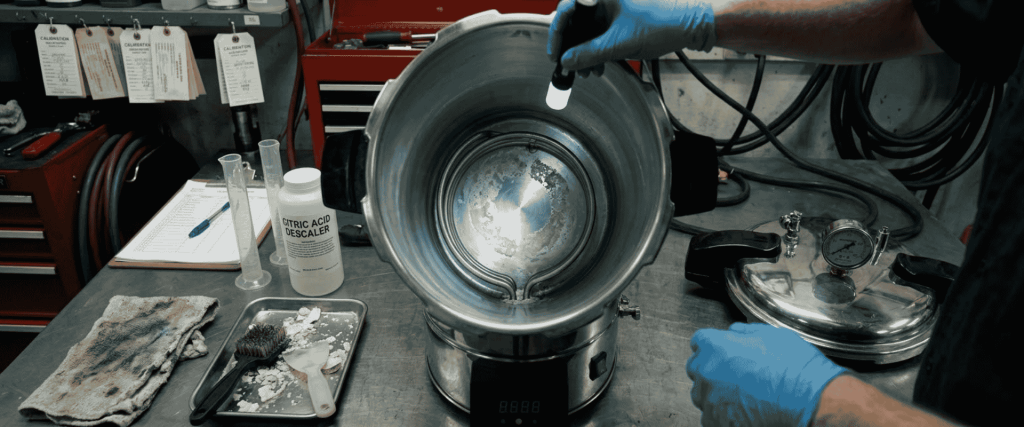 BKM-P18I Portable Autoclave being cleaned and maintained on a laboratory workbench with tools and descaler