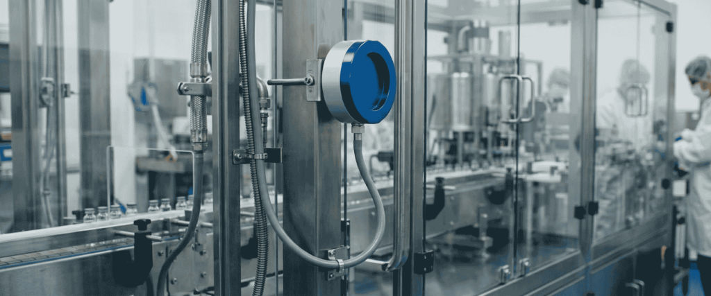 EU GMP Annex 1 sterile pharmaceutical filling line with stainless steel equipment, glass barriers, conveyor, and operators