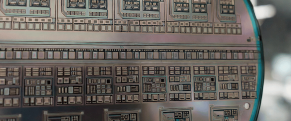 Photolithography wafer with intricate semiconductor circuit patterns, showing detailed microchip design and precision engineering