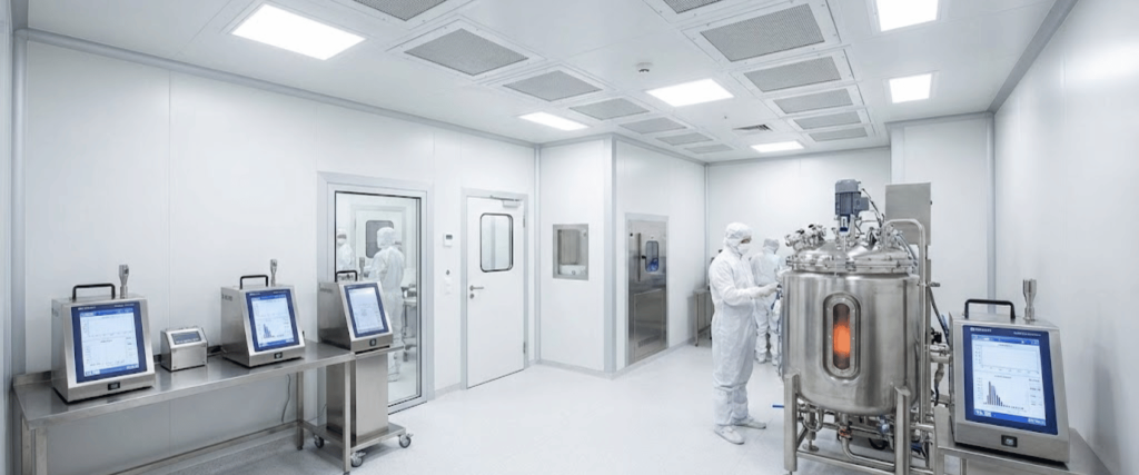 Sterile stainless-steel laboratory with workstations, computers, equipment and bright ceiling lights in a cleanroom setting