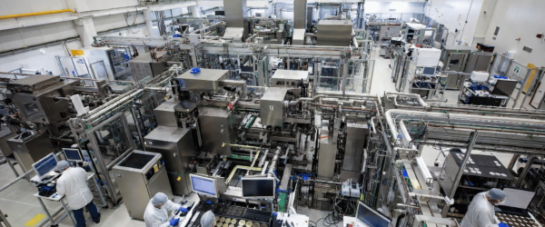 Particle manufacturing facility with automated machines, workers in clean suits, and advanced industrial production lines