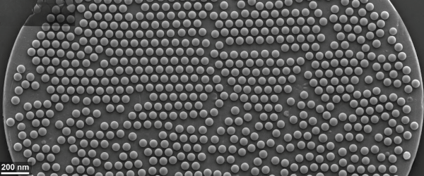 Sub-20nm PSL SEM image of densely packed, uniform nanoscale polymer spheres on a circular substrate, 200 nm scale bar visible