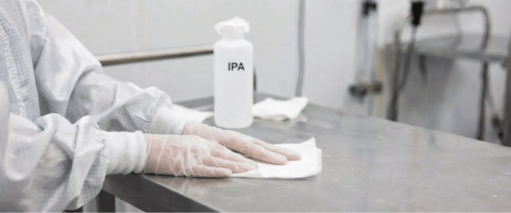 ISO Class 5 Cleanroom technician cleaning a stainless steel work surface with IPA for sterile contamination control