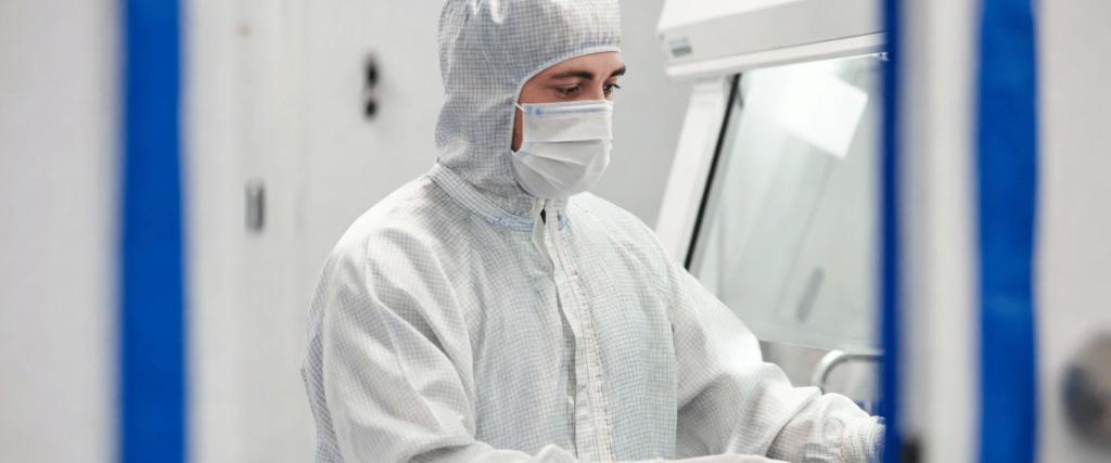 ISO Class 5 Cleanroom technician in protective suit working in sterile manufacturing environment with precision equipment