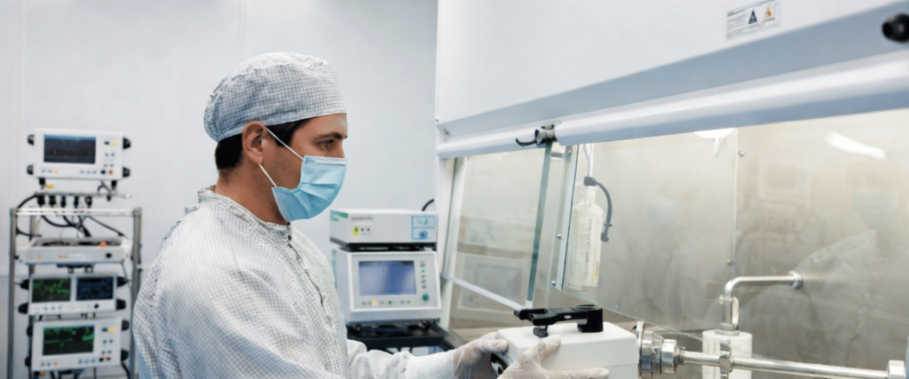 ISO Class 5 Cleanroom technician operating sterile equipment in a controlled lab with monitored medical systems and safety gear