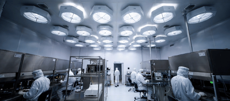 ISO Class 5 Cleanroom with technicians in protective suits working under HEPA filters in a sterile pharmaceutical lab environment
