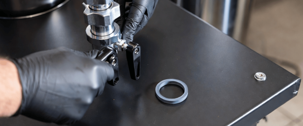 Elga UV technician wearing gloves adjusts a stainless steel component on industrial equipment during maintenance