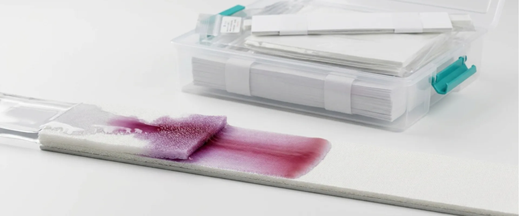 Lateral Flow test strip showing purple sample reaction beside a stack of packaged test cards in a clean white lab setting