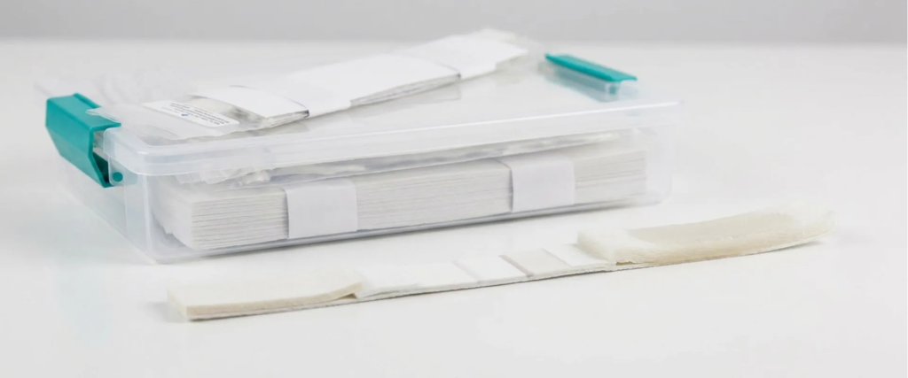 Lateral Flow test strips in a clear plastic case with folded strips and a sample strip on a white background, medical kit